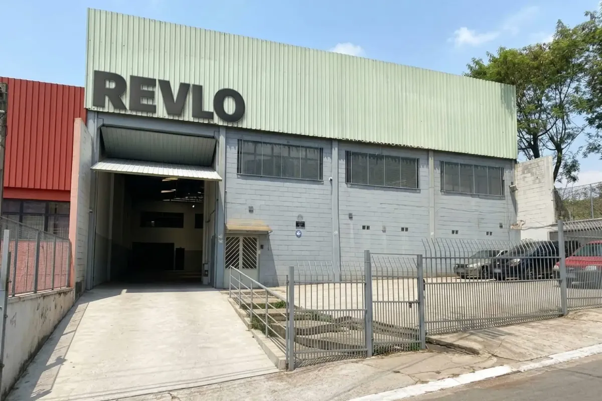 Fachada da fábrica da Revlo em Barueri, com o letreiro REVLO sobre o portão de carga