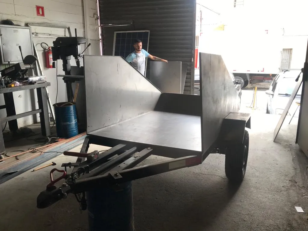 Carreta de chapa dobrada em montagem na oficina da Revlo em 2021, com um montador segurando uma chapa ao fundo