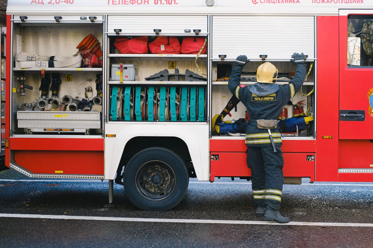 Bombeiro retirando equipamento do compartimento de uma viatura de resgate