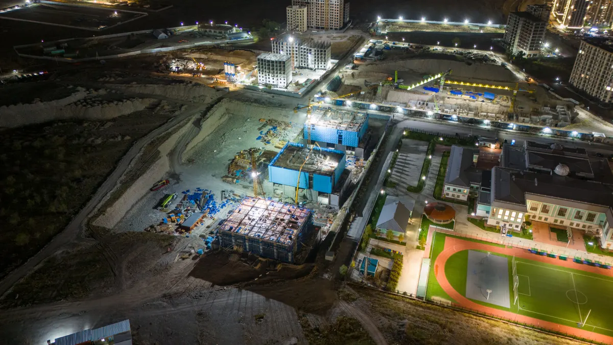 Vista aérea de canteiro de obras com as frentes de trabalho acesas durante a noite