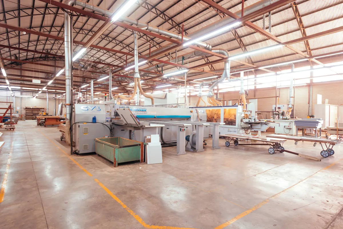 Interior de galpão fabril amplo com luminárias acesas ao longo do telhado
